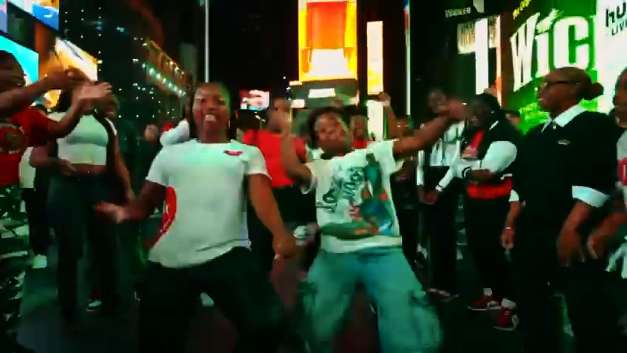 Dancers in red and white celebrate mid-routine in Times Square at night