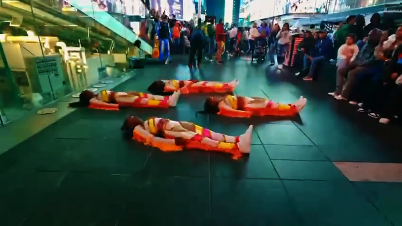 The team ends the routine lying in formation on the plaza floor