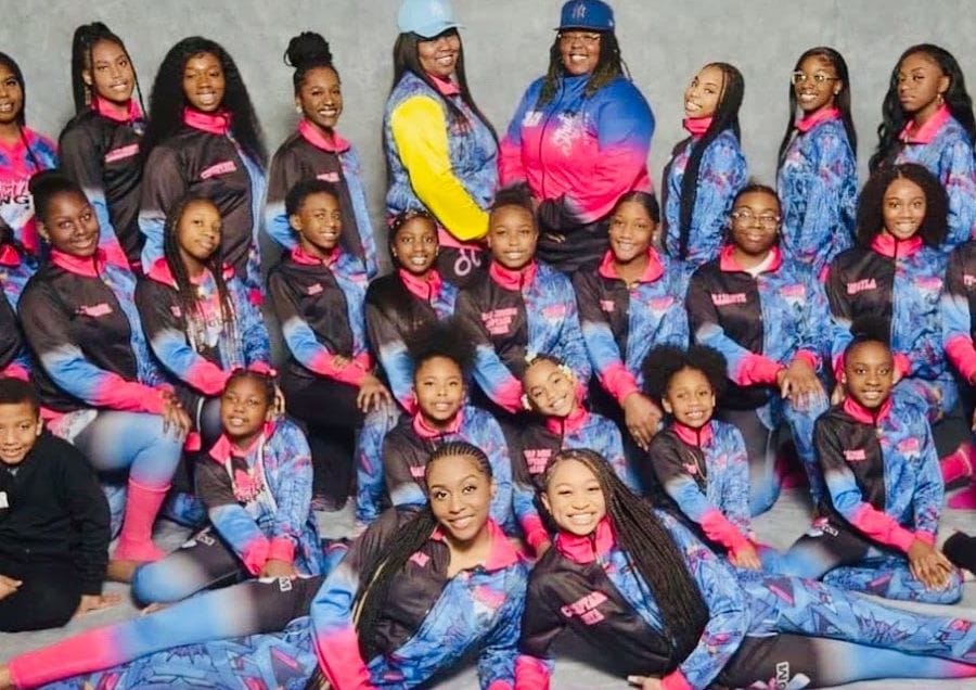 Strut N Strive dancers and coaches posed together in matching team jackets
